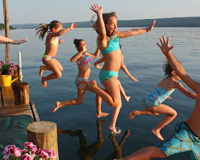 A group young children jumping into a New Hampshire lake