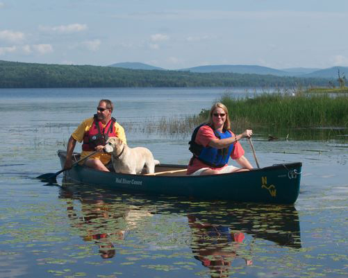 A man and a woman share a canoe with their dog