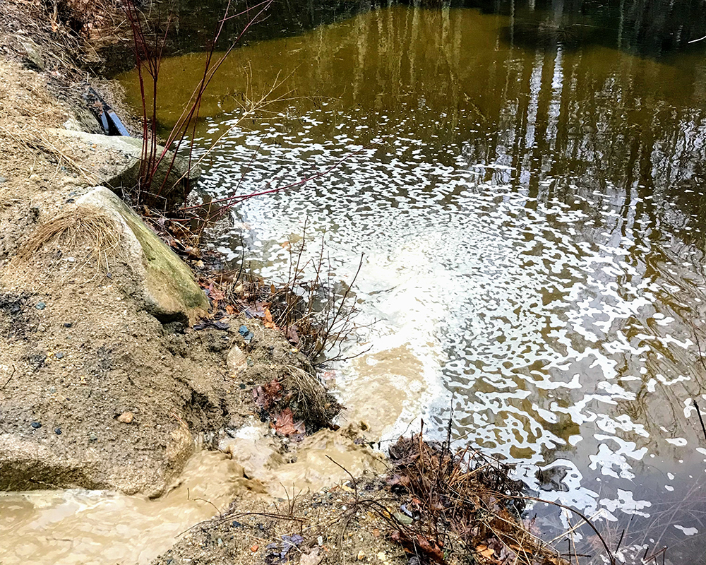 Image of water running and streaming into larger and separate body of water.